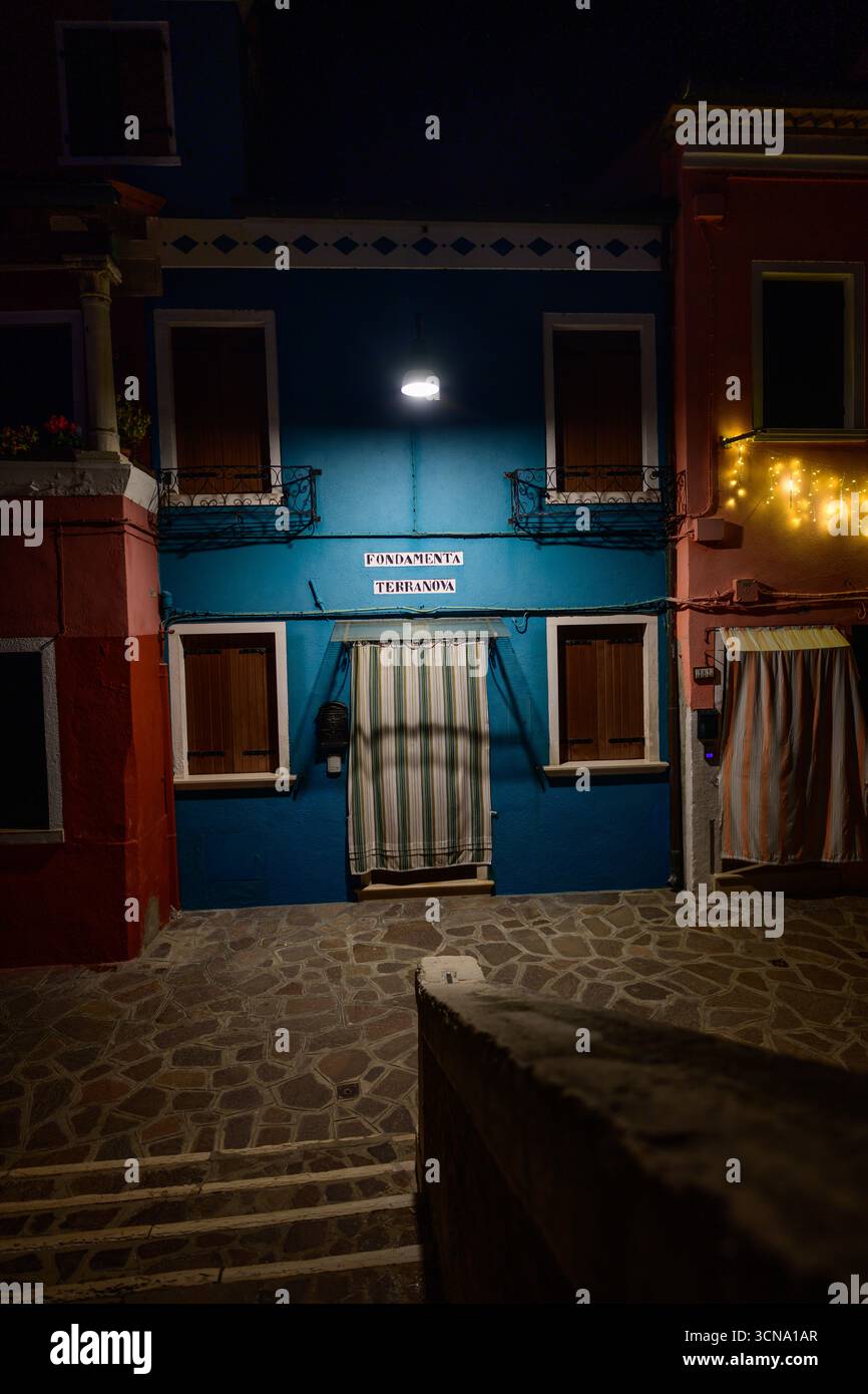 Burano, Italia - dicembre 28 2025: Colorata facciata della Casa Blu illuminata di notte sulla fondamenta Terranova sull'Isola di Burano nella Laguna di Venezia. Foto Stock