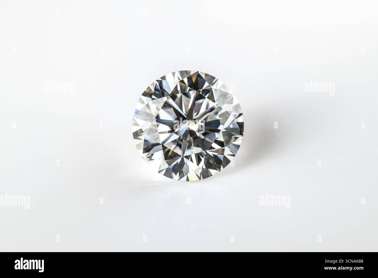 Un diamante bianco è seduto su uno sfondo bianco. Il diamante è il fuoco principale dell'immagine, ed è la cosa più importante della scena. Il whi Foto Stock