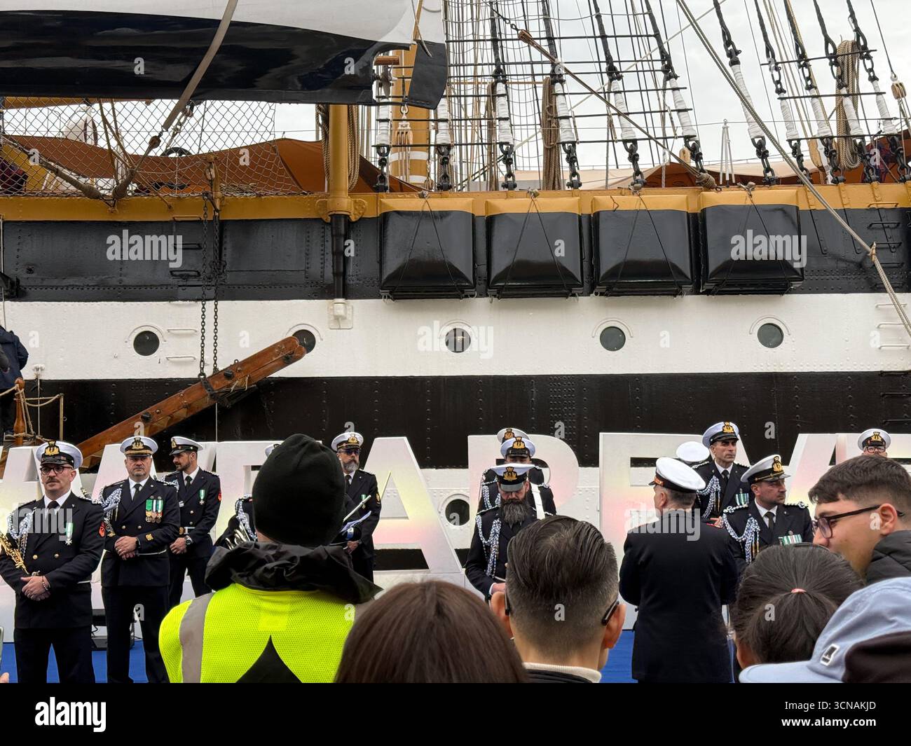 Gli ufficiali della Marina militare italiana si schierarono di fronte alla storica nave a vela Amerigo Vespucci, ormeggiata a Riva San Biasio durante lo scalo di Venezia, in Italia - Immagine stock catturata con smartphone