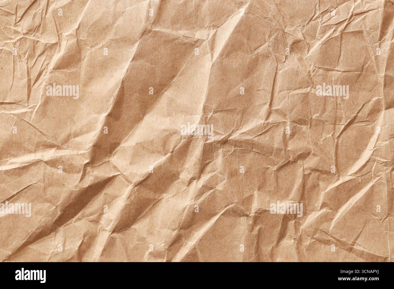 Carta kraft con trama marrone. Superficie di sfondo increspata per la progettazione. Materiale di imballaggio ecologico. Foglio di carta ruvida con pieghe e pieghe. Foto Stock