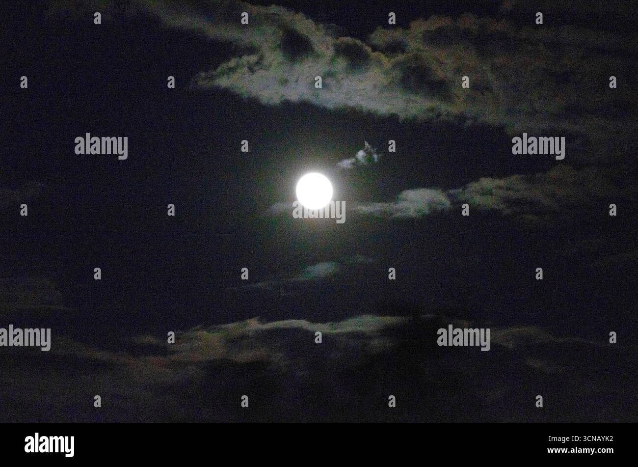 Mesmorising scena notturna di una Luna piena circondata da nuvole Foto Stock