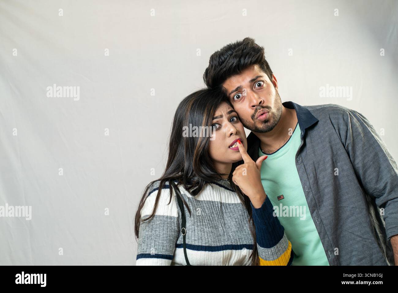 Una giovane coppia in posa per una foto dal look sorpreso ed espressivo. Coppia con espressioni curiose - Studio Portrait Foto Stock