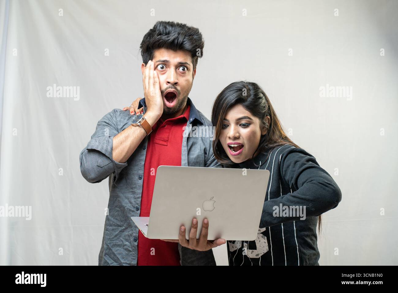 Una giovane coppia con un'espressione scioccata che guarda un notebook. Foto Stock