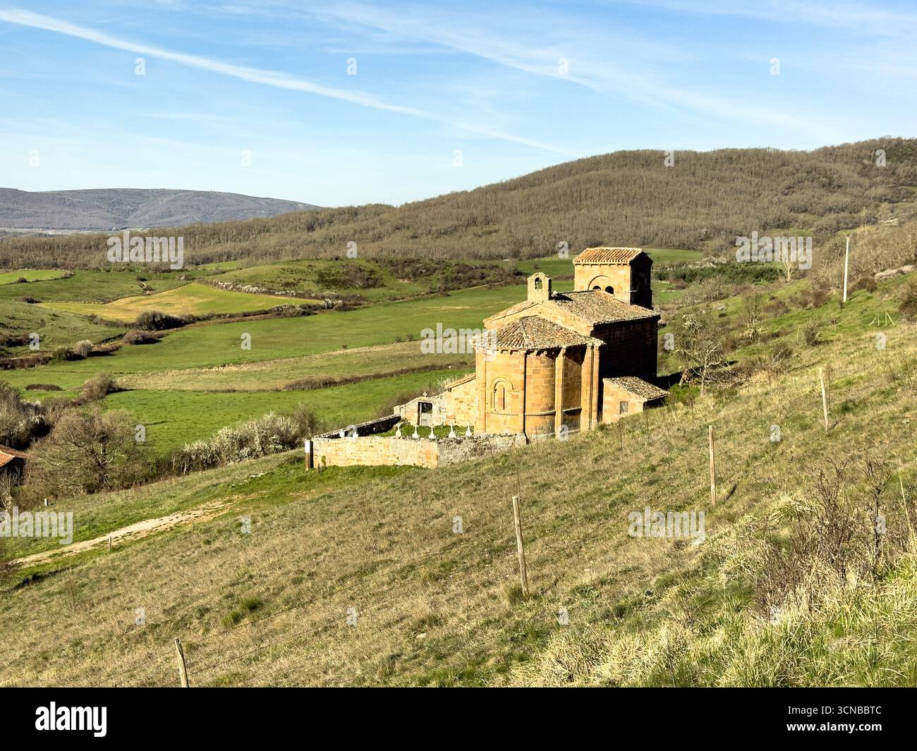 Storica chiesa romanica con pareti in pietra, tetto in piastrelle rosse e campanile annidato nella campagna di Palencia. Foto Stock