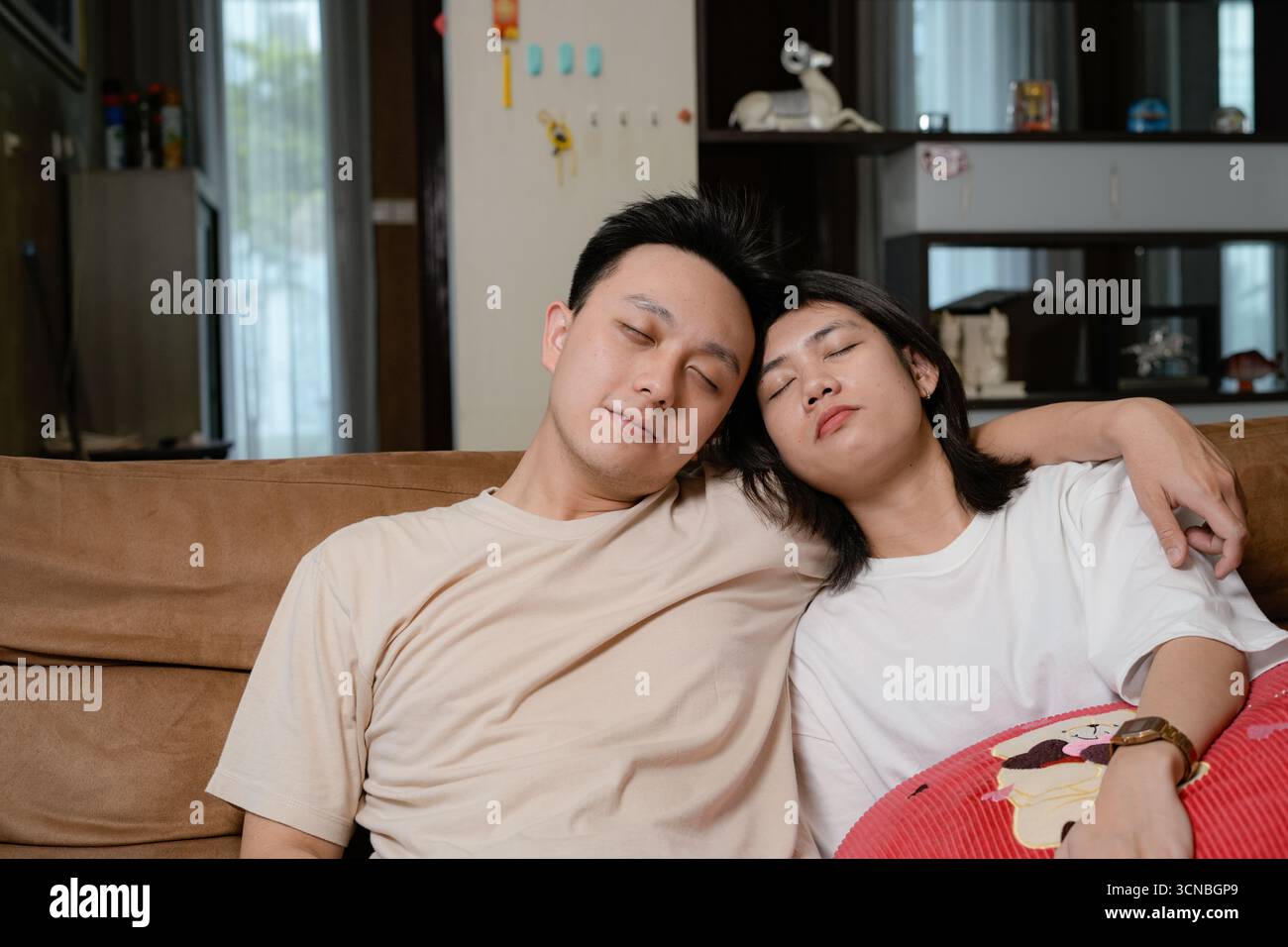 Una tranquilla scena di una coppia che riposa su un divano marrone a casa Foto Stock
