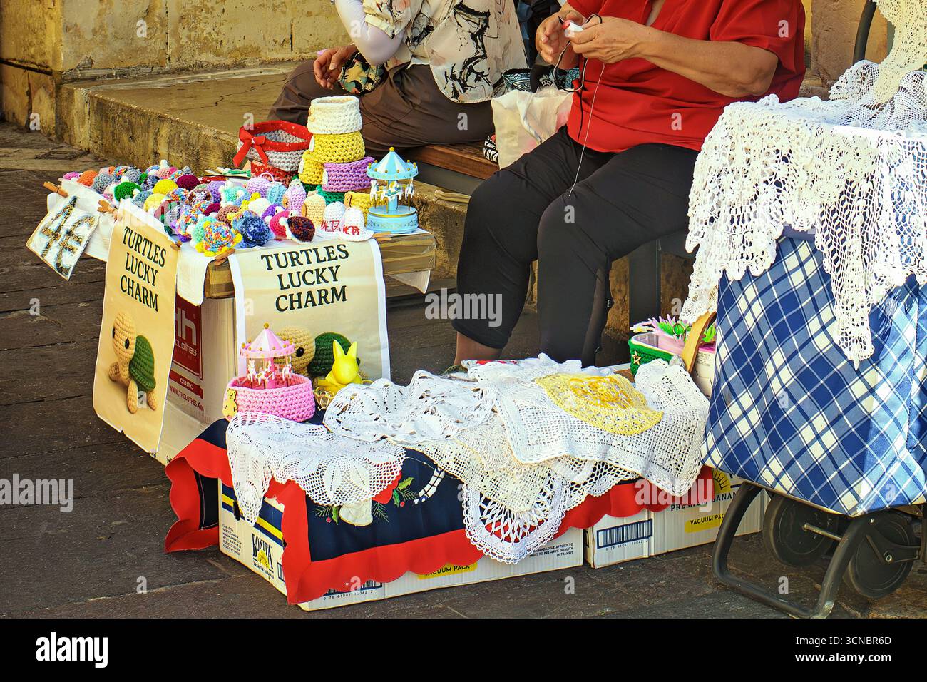 La Valletta, Malta - 09.17.2025: Souvenir fatti a mano all'uncinetto: Pizzi, doilies e tartarughe giocattolo in una bancarella del mercato di strada. Foto Stock