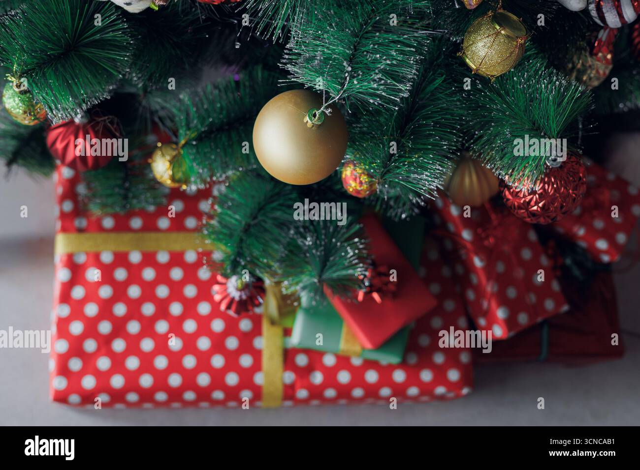 Primo piano di regali e ornamenti natalizi sotto un albero decorato, mostrando colori, texture e atmosfera natalizia per i disegni stagionali Foto Stock