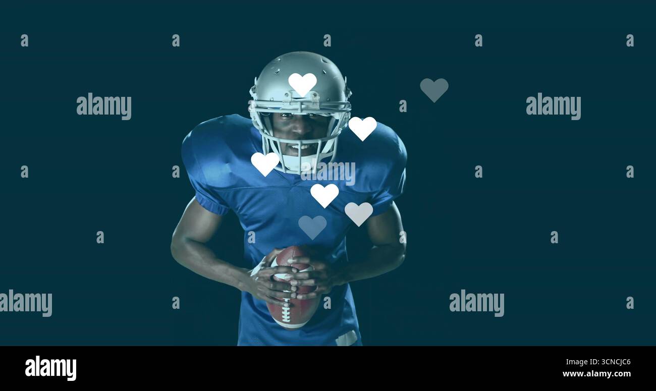 Giocatore che indossa un casco argentato e una maglia blu che regge il calcio in studio, con icone a forma di cuore galleggiante Foto Stock