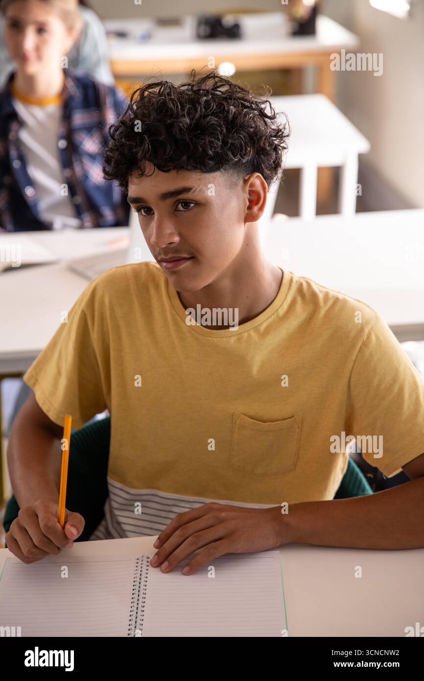 Diversi compagni di classe adolescenti che scrivono su quaderni con matite Foto Stock