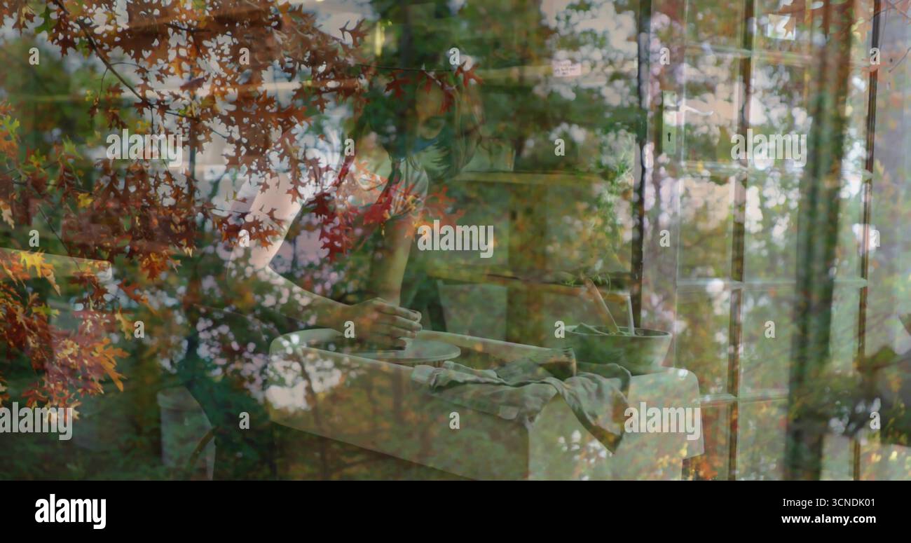 Vasaio che indossa un grembiule grigio sulla ruota girevole in officina, rivestimento delle foglie autunnali Foto Stock