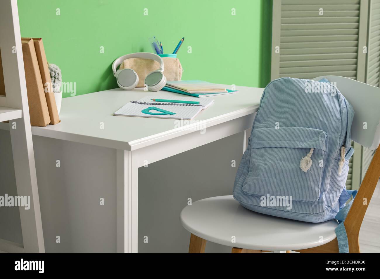 Posto di lavoro con cancelleria scolastica e zaino nella stanza dei bambini Foto Stock