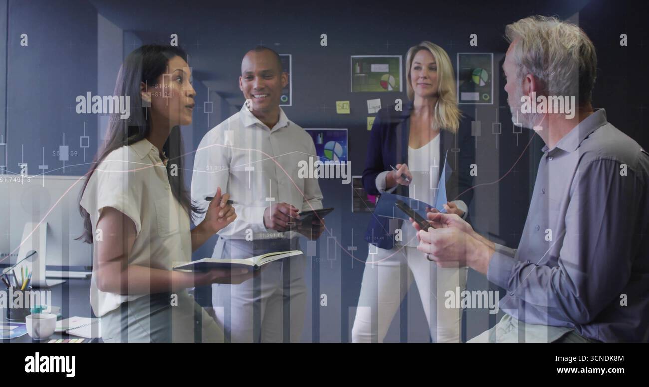 Discutere di quattro professionisti che indossano tute utilizzando tablet nell'area conferenze, con grafici finanziari Foto Stock