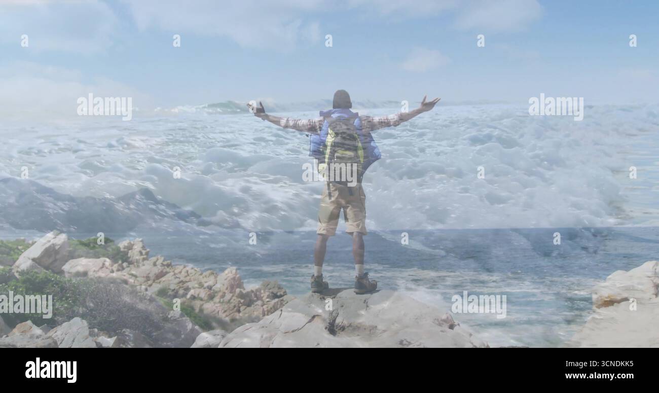 Spalmare le braccia con l'attrezzatura da trekking sulla scogliera rocciosa costiera, con un grande zaino e stivali da trekking Foto Stock