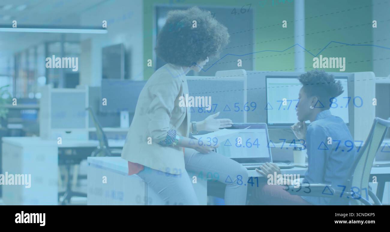 Collaborazione tra donne che discutono di progetti alla scrivania open space, con tablet e monitor Foto Stock