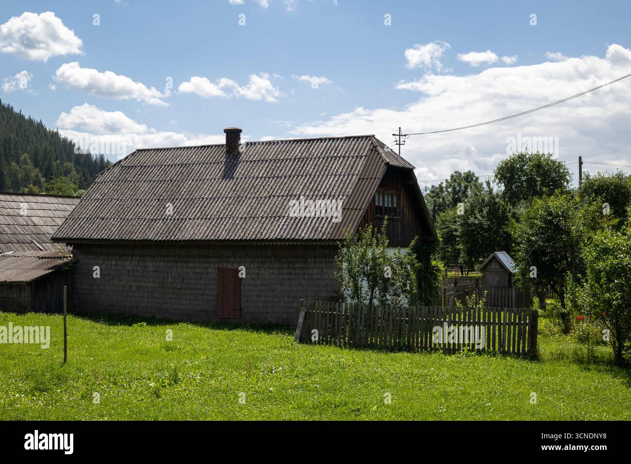 un tradizionale fienile rustico con un tetto testurizzato sorge in un vibrante campo verde, circondato da una semplice recinzione in legno. la scena serena è contro Foto Stock