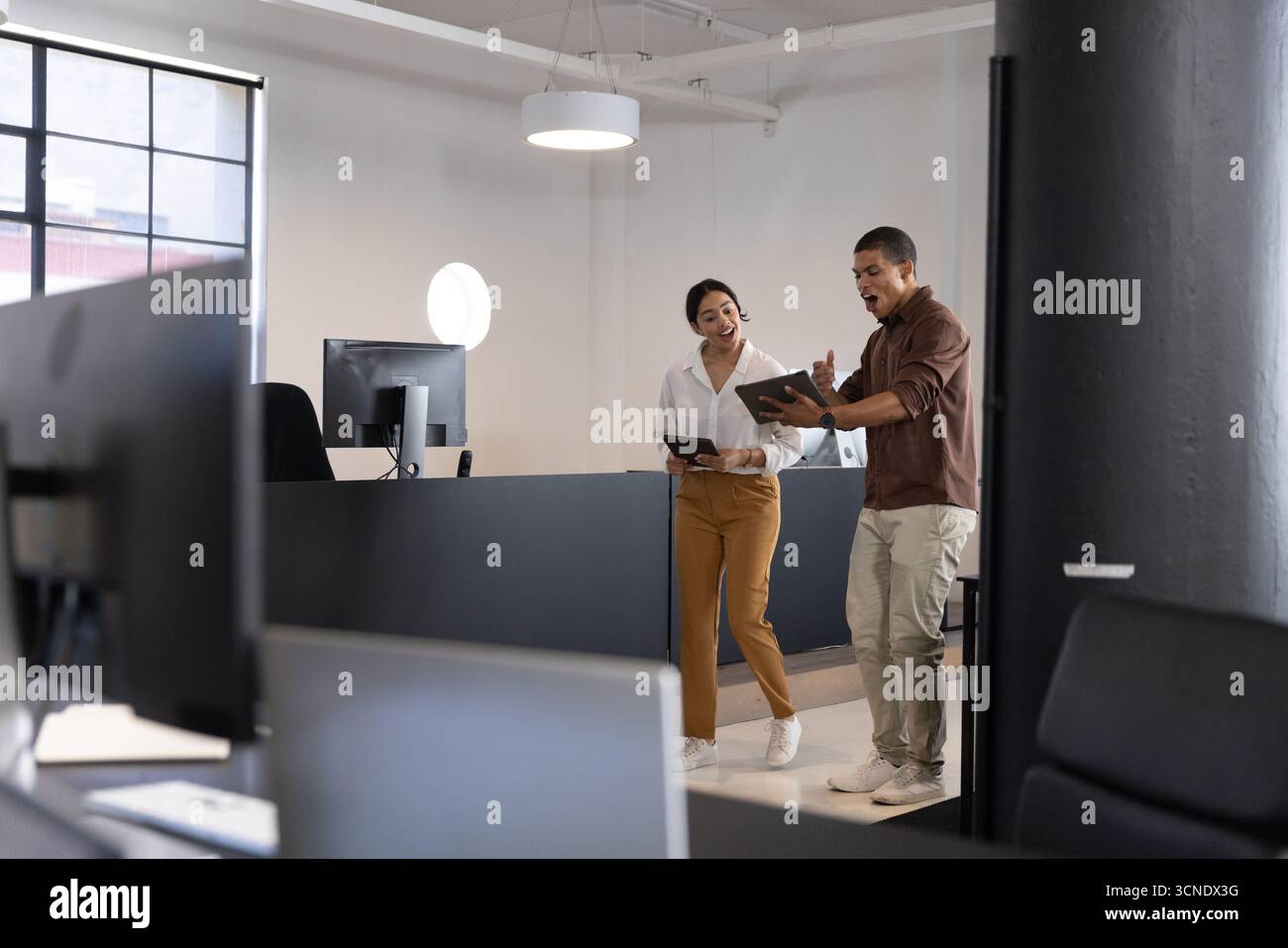 Colleghi che tengono in mano tablet e rivedono i dati in un moderno ufficio open space, monitorano e spazio di copia Foto Stock