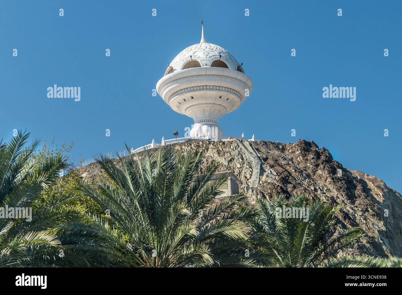 Oman - Mascate - Riyam Park - il monumento al bruciatore di incenso gigante incorona una collina rocciosa sopra lussureggianti palme da dattero Foto Stock