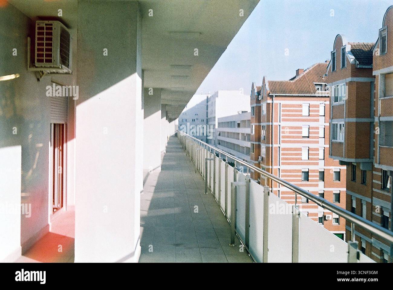 Vista da una terrazza verso terrazze ripetitive che si estendono all'infinito, creando una composizione architettonica moderna ipnotica nei toni della pellicola analogica. Foto Stock