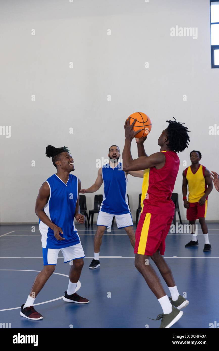 Uomo afro-americano che indossa un'uniforme per saltare e sparare a pallacanestro sul campo, copia spazio Foto Stock