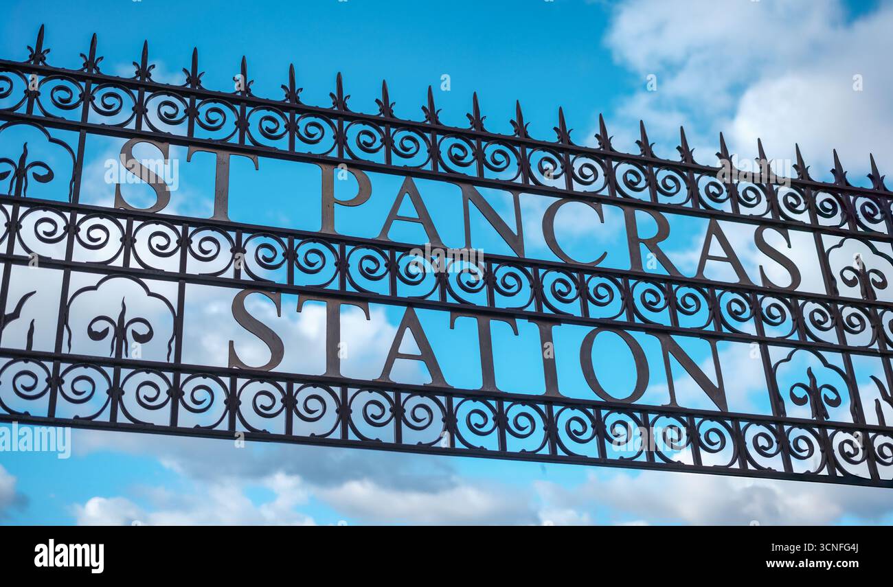 Insegna di Iron Marquee decorata d'epoca che legge la stazione di St Pancras a Londra, contro il cielo blu e le nuvole Foto Stock