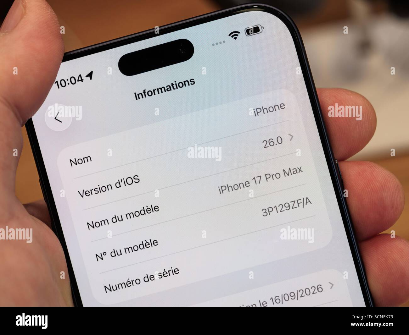 Primo piano dello smartphone Apple iPhone 17 Pro Max che mostra la schermata delle informazioni del dispositivo con la versione del sistema iOS 26 e i dettagli tecnici del modello visualizzati su t Foto Stock