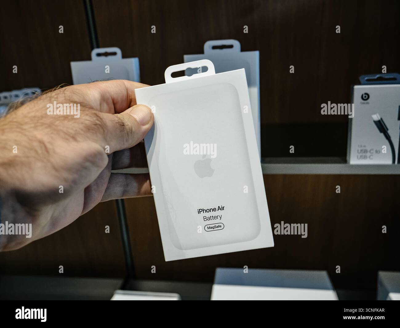 Parigi, Francia - 19 settembre 2025: Una mano regge la batteria Apple iPhone Air con confezione MagSafe, esposta tra gli altri accessori sugli scaffali all'interno di un Foto Stock