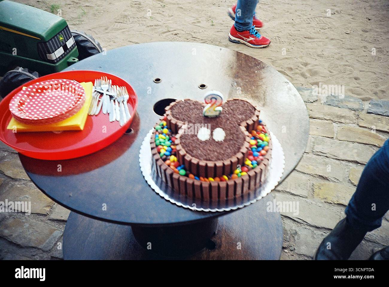 Foto di film lo-fi di una torta di compleanno con una candela numero due, scattata con un Lomo LC-A. Messa a fuoco morbida, sfocatura analogica e atmosfera nostalgica per i bambini. Foto Stock