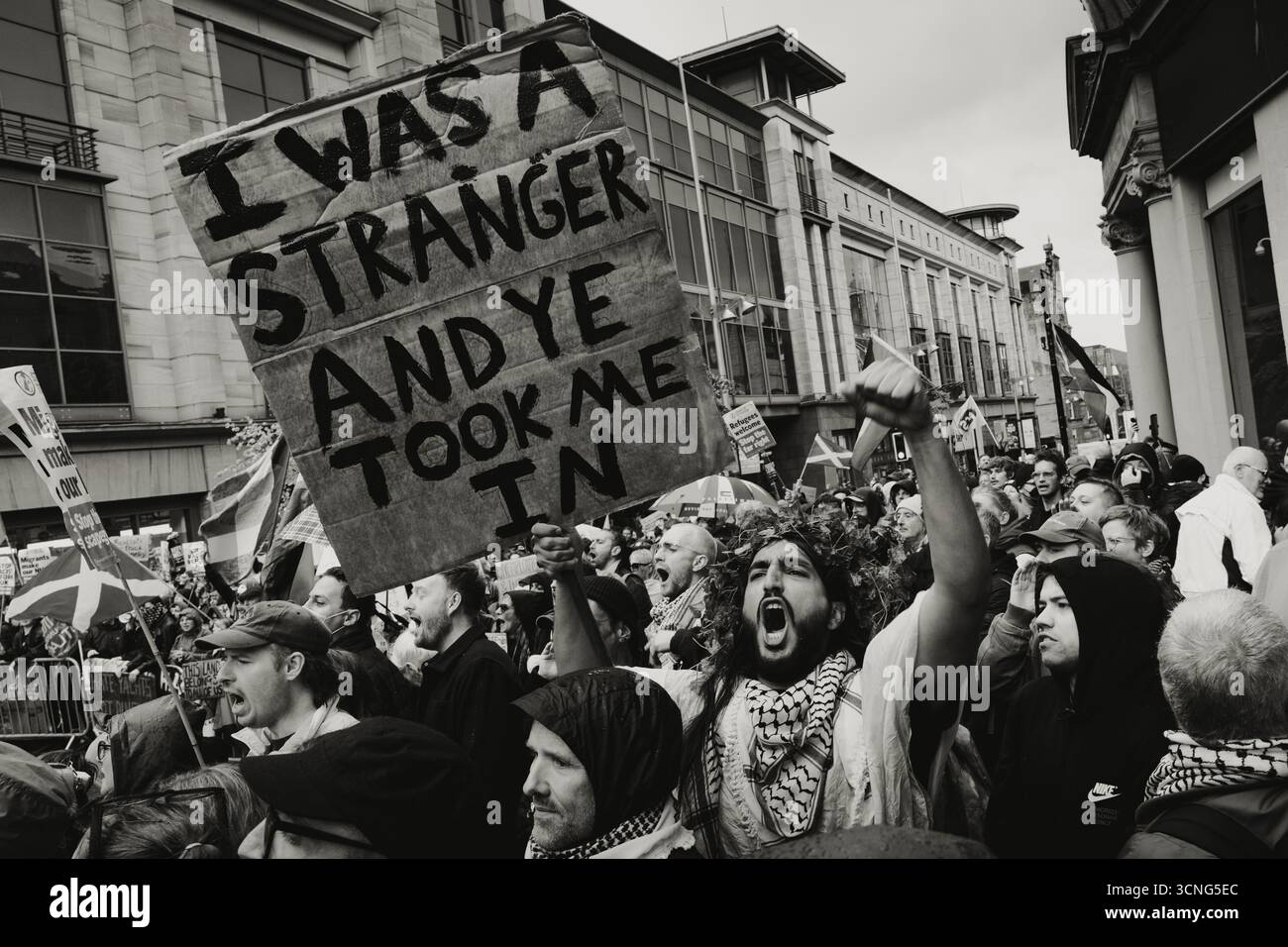 Contro manifestante della protesta anti-immigrazione "Unity" a Glasgow con un cartello Foto Stock