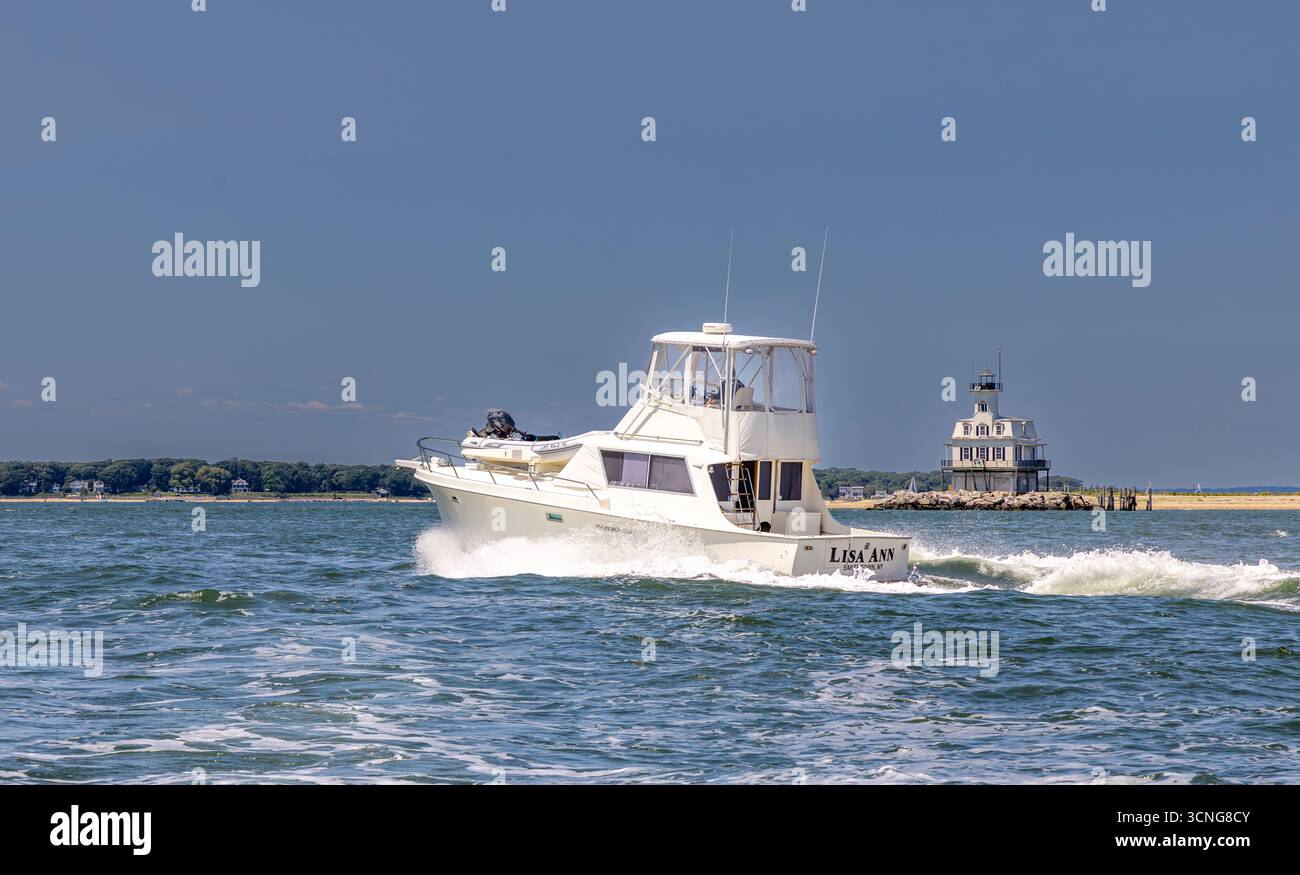 yacht a motore, lisa ann in corso con una casa di luci di insetti sullo sfondo Foto Stock