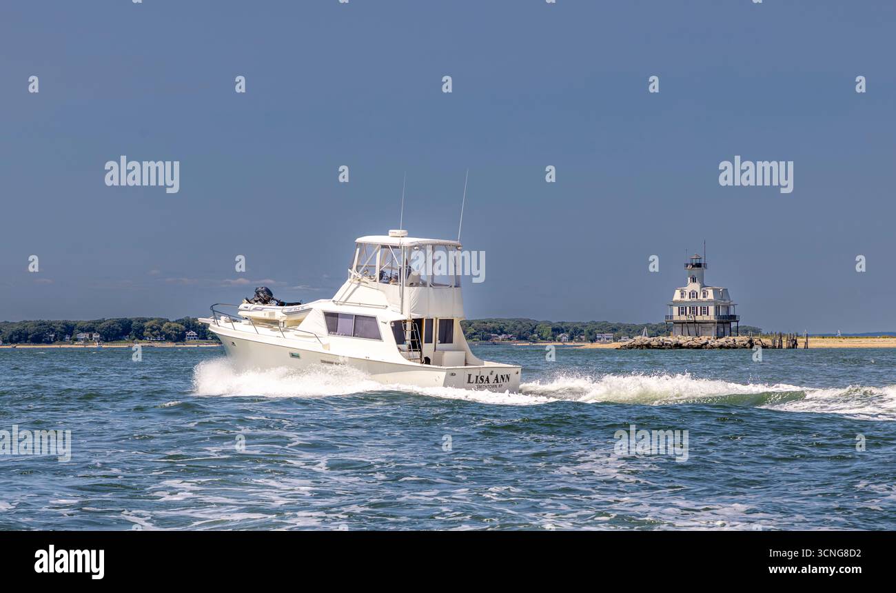yacht a motore, lisa ann in corso con una casa di luci di insetti sullo sfondo Foto Stock