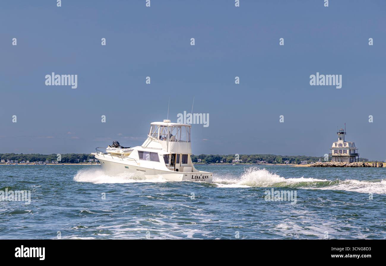 yacht a motore, lisa ann in corso con una casa di luci di insetti sullo sfondo Foto Stock