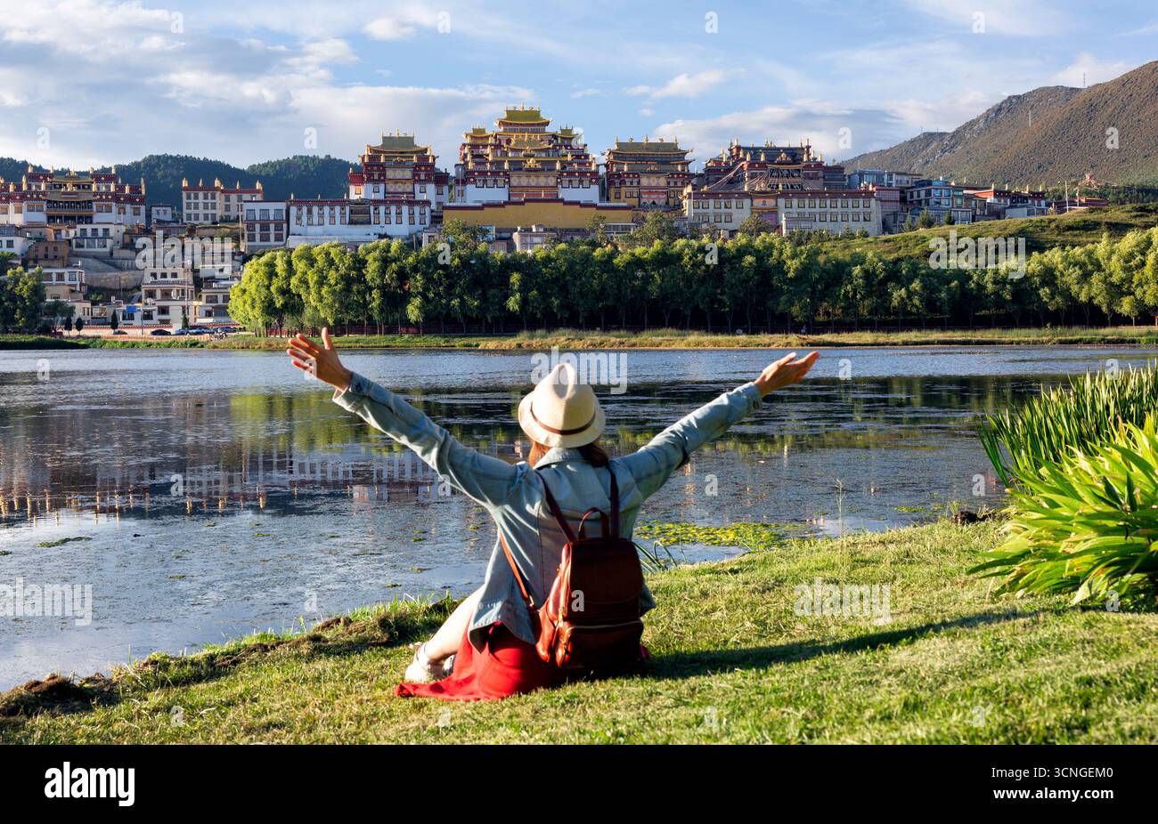 Giovane donna asiatica seduta di fronte al Monastero di Songzanlin in Cina, una famosa attrazione turistica in Asia per i viaggi estivi. Foto Stock