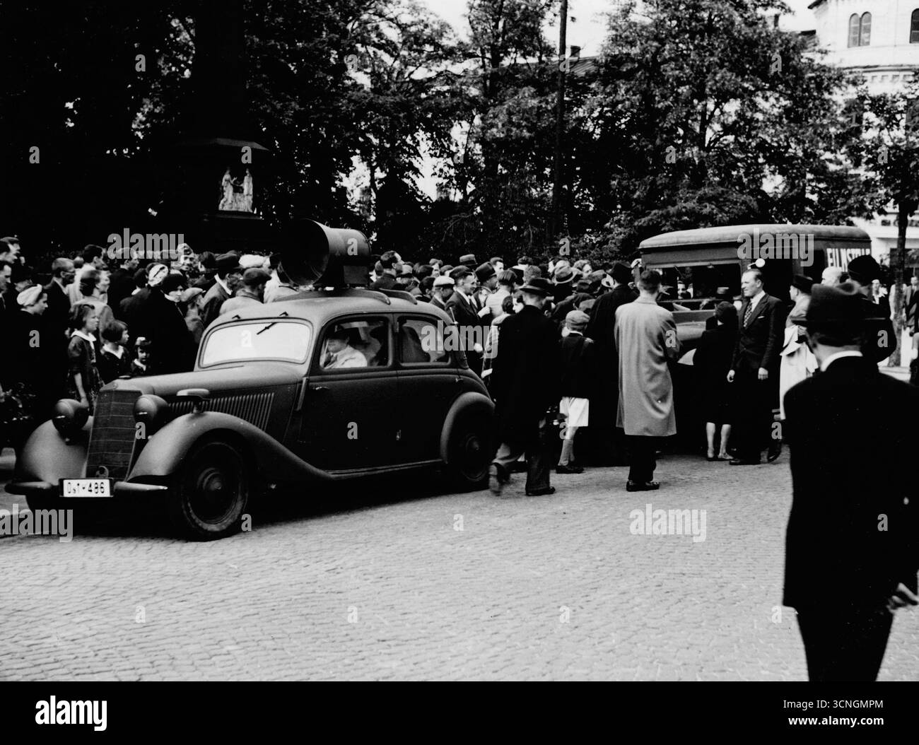 Un'auto del dipartimento di propaganda tedesco - una Mercedes 170 V con un megafono sul tetto - si trova ad Adolf Hitler Platz. Una folla di persone è visibile. Seconda guerra mondiale, Germania degli anni '1940 Foto Stock