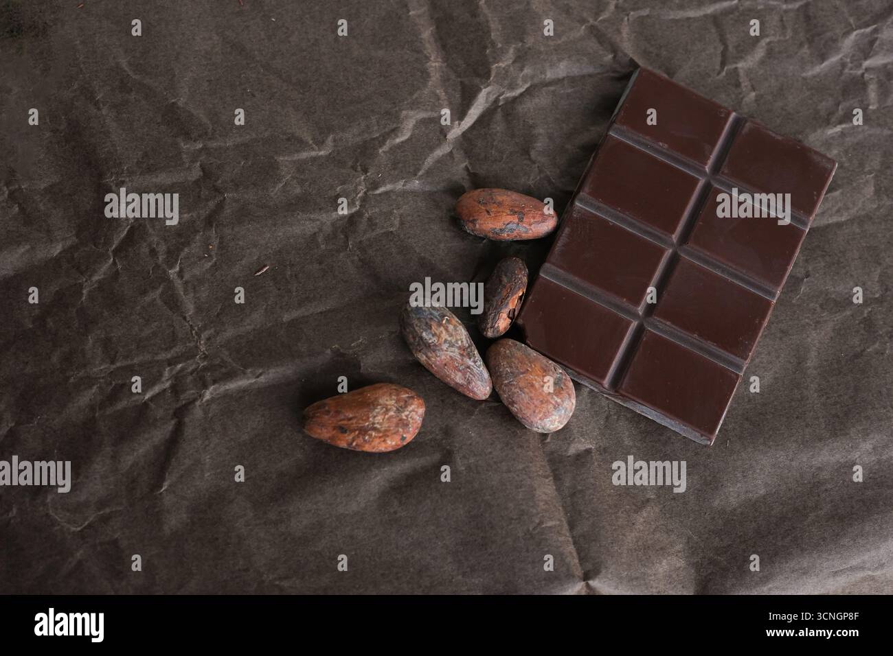 Fagioli di cacao. Barretta di cioccolato. Produzione di cioccolato Bean-to-bar. Carta da imballaggio marroni. Copia spazio. Profondità di campo bassa. Foto Stock