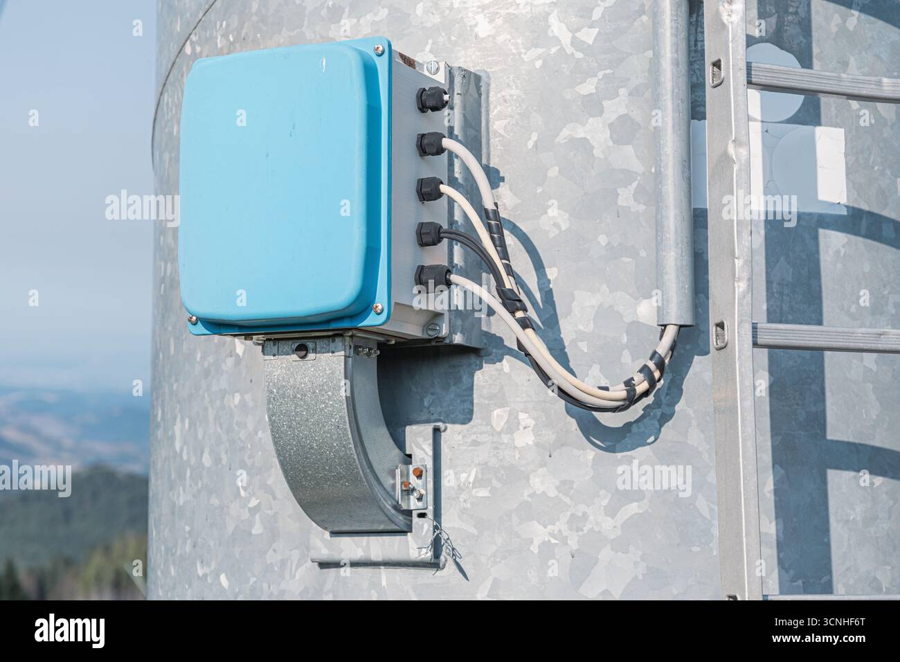 Primo piano di una scatola di derivazione elettrica fissata a una torre di turbine eoliche in acciaio galvanizzato, garantendo una distribuzione dell'energia sicura ed efficiente Foto Stock