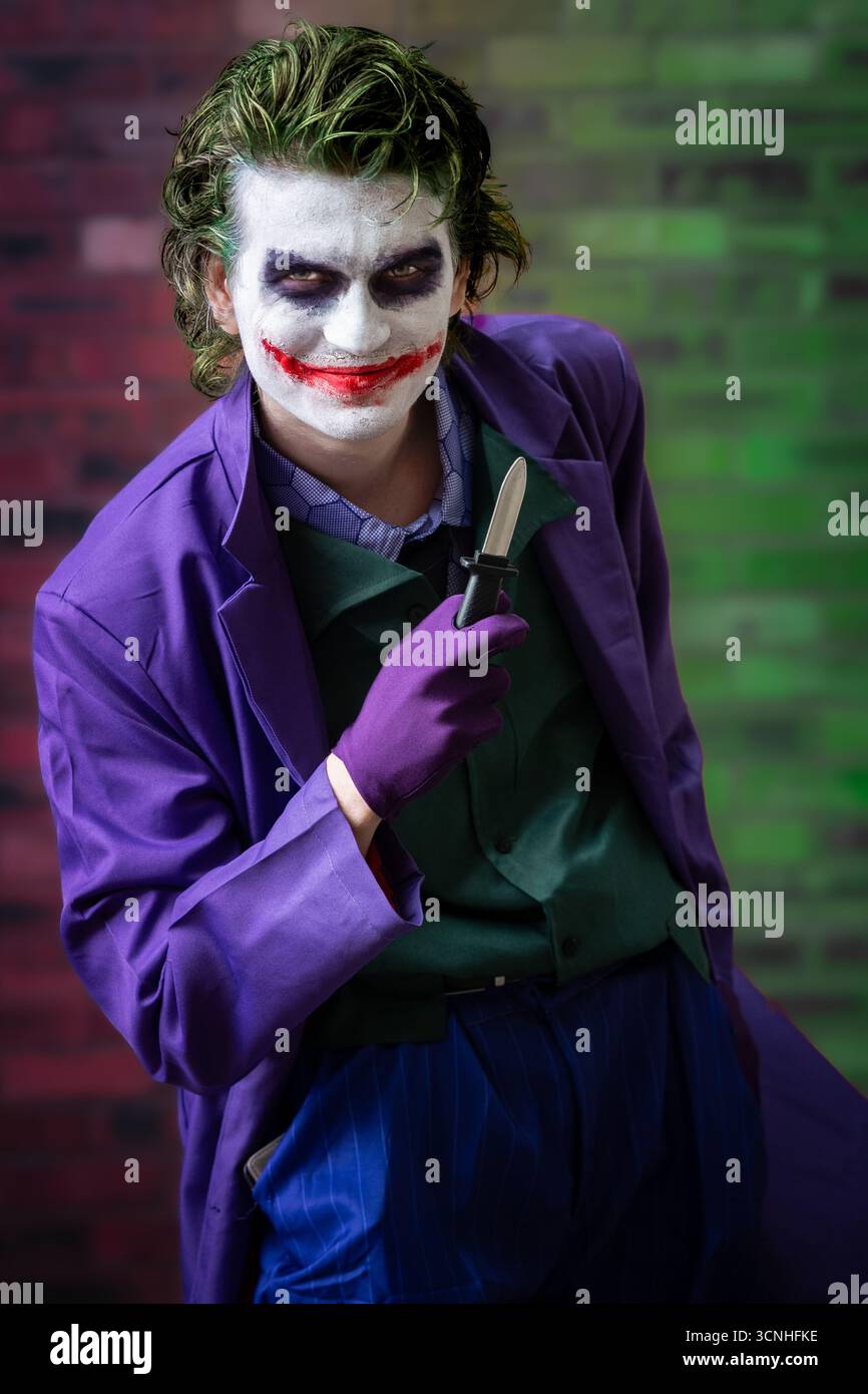 Ritratto di un giovane cosplayer maschile vestito da Joker e divertiti mentre sorridi e guarda direttamente la fotocamera con spazio di copia Foto Stock