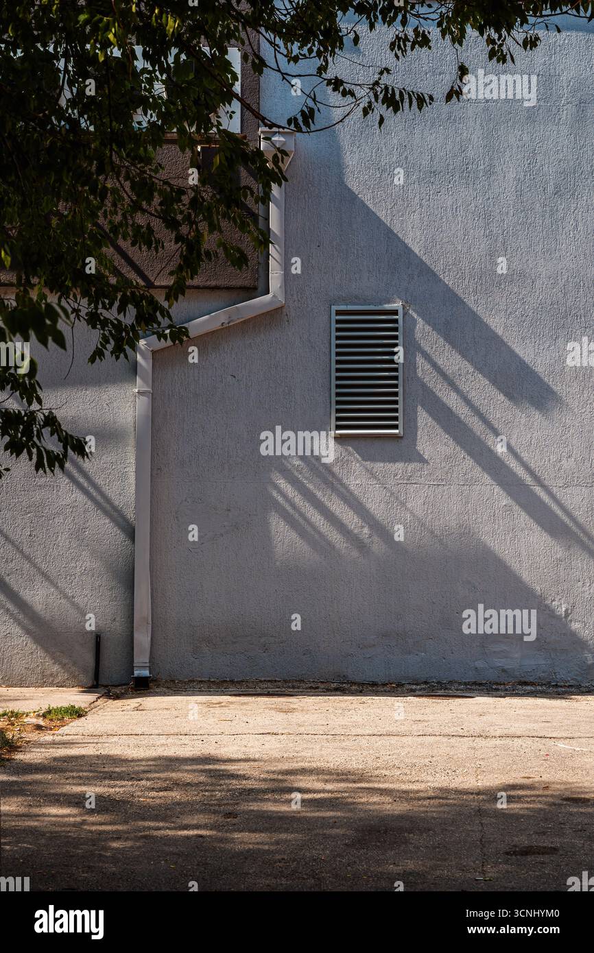 Ombreggiature a griglia di ventilazione su pareti in cemento con gocciolatoio e dettagli urbani. Immagine verticale. Foto Stock