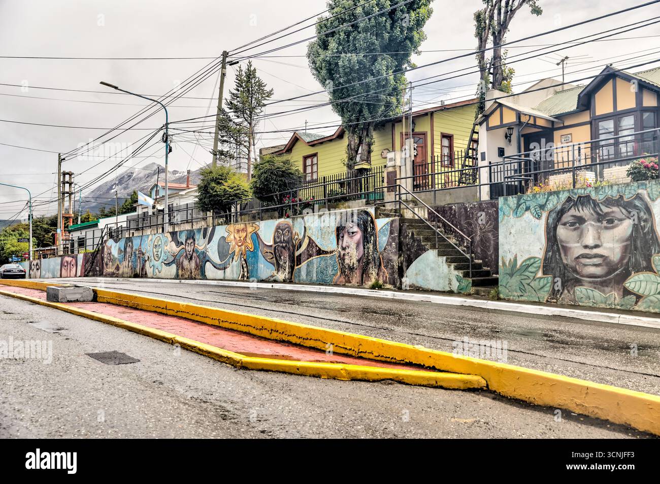 Colorato murale all'aperto lungo una strada residenziale a Ushuaia, che ritrae i popoli indigeni della Terra del fuoco, tra cui Yaghan e Selk'nam fi Foto Stock