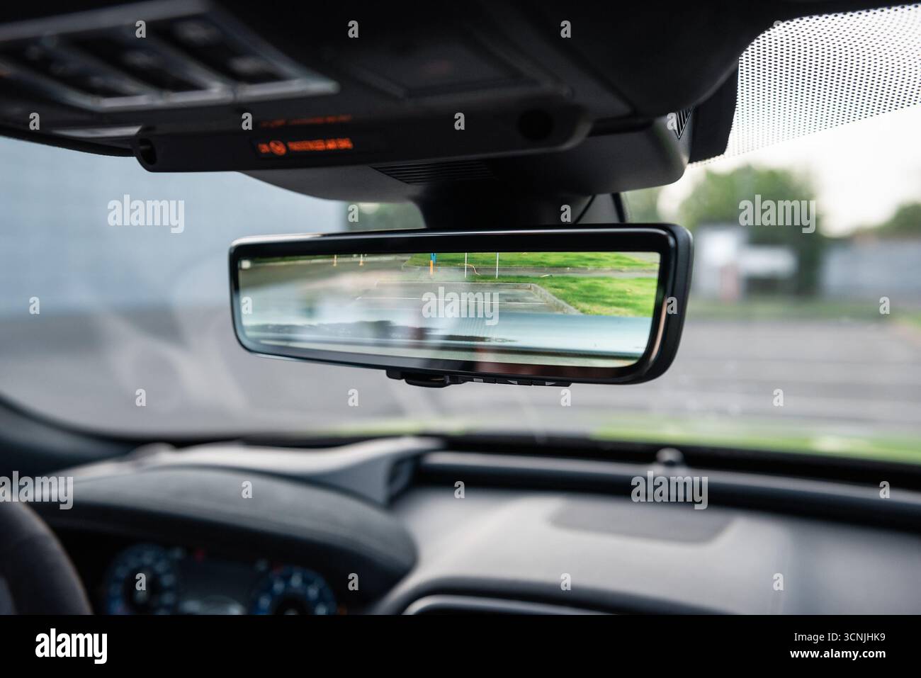 Specchietto retrovisore della telecamera posteriore. Schermo all'interno di uno specchietto retrovisore di un veicolo che mostra l'immagine della telecamera di retromarcia, del pannello anteriore e del cruscotto nella parte posteriore. Foto Stock