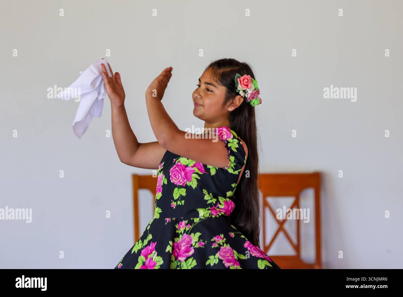 Una giovane coppia esegue la tradizionale danza cueca cilena, vestita con vivaci costumi folcloristici, all'interno di un luogo culturale. Foto Stock