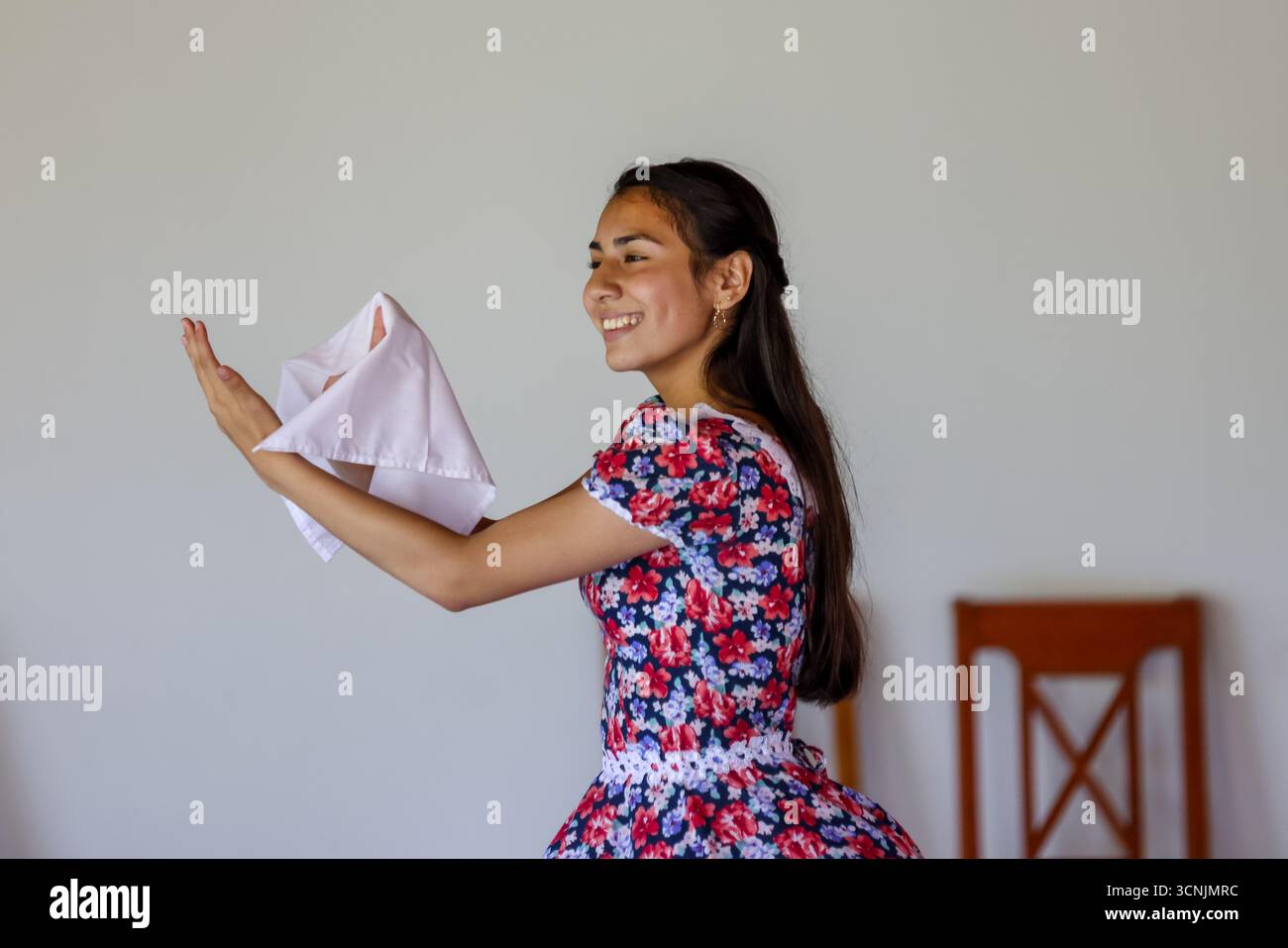 Una giovane coppia esegue la tradizionale danza cueca cilena, vestita con vivaci costumi folcloristici, all'interno di un luogo culturale. Foto Stock
