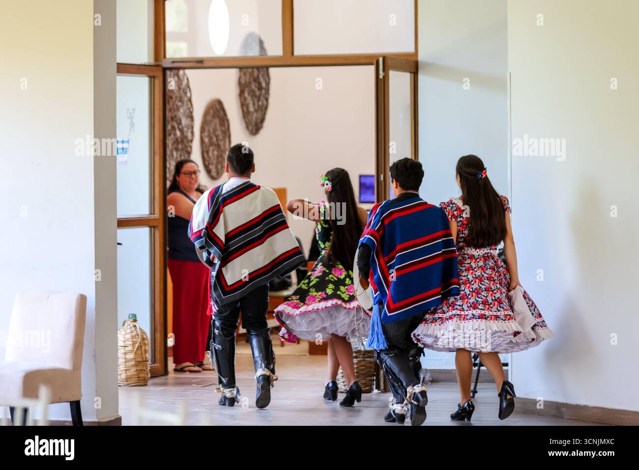 Una giovane coppia esegue la tradizionale danza cueca cilena, vestita con vivaci costumi folcloristici, all'interno di un luogo culturale. Foto Stock