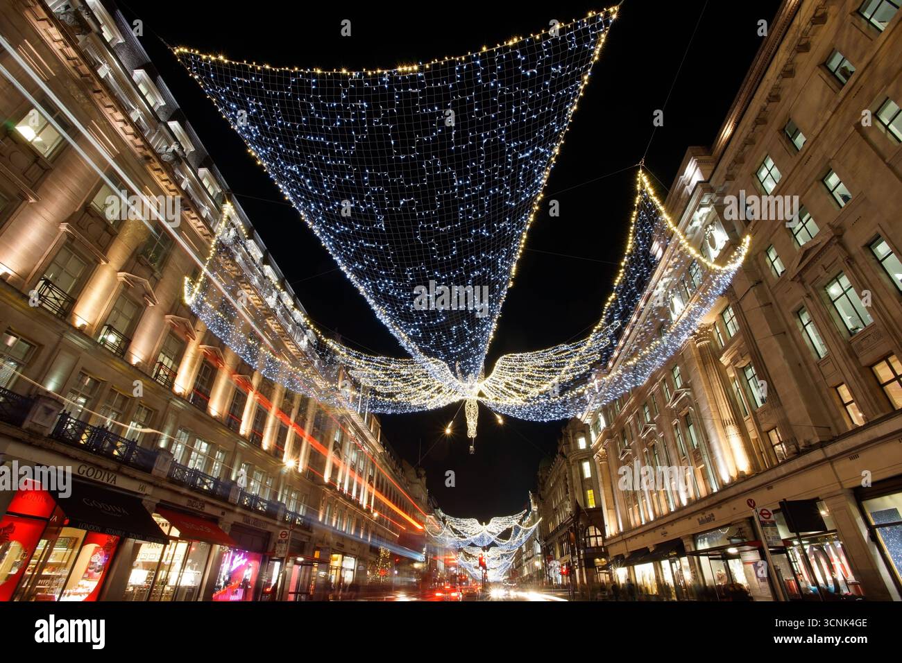 LONDRA, REGNO UNITO. 17 DICEMBRE 2016. Regent Street illuminata con luci d'angelo natalizio, mentre i fari di auto e autobus creano piste luminose dinamiche di notte. Foto Stock