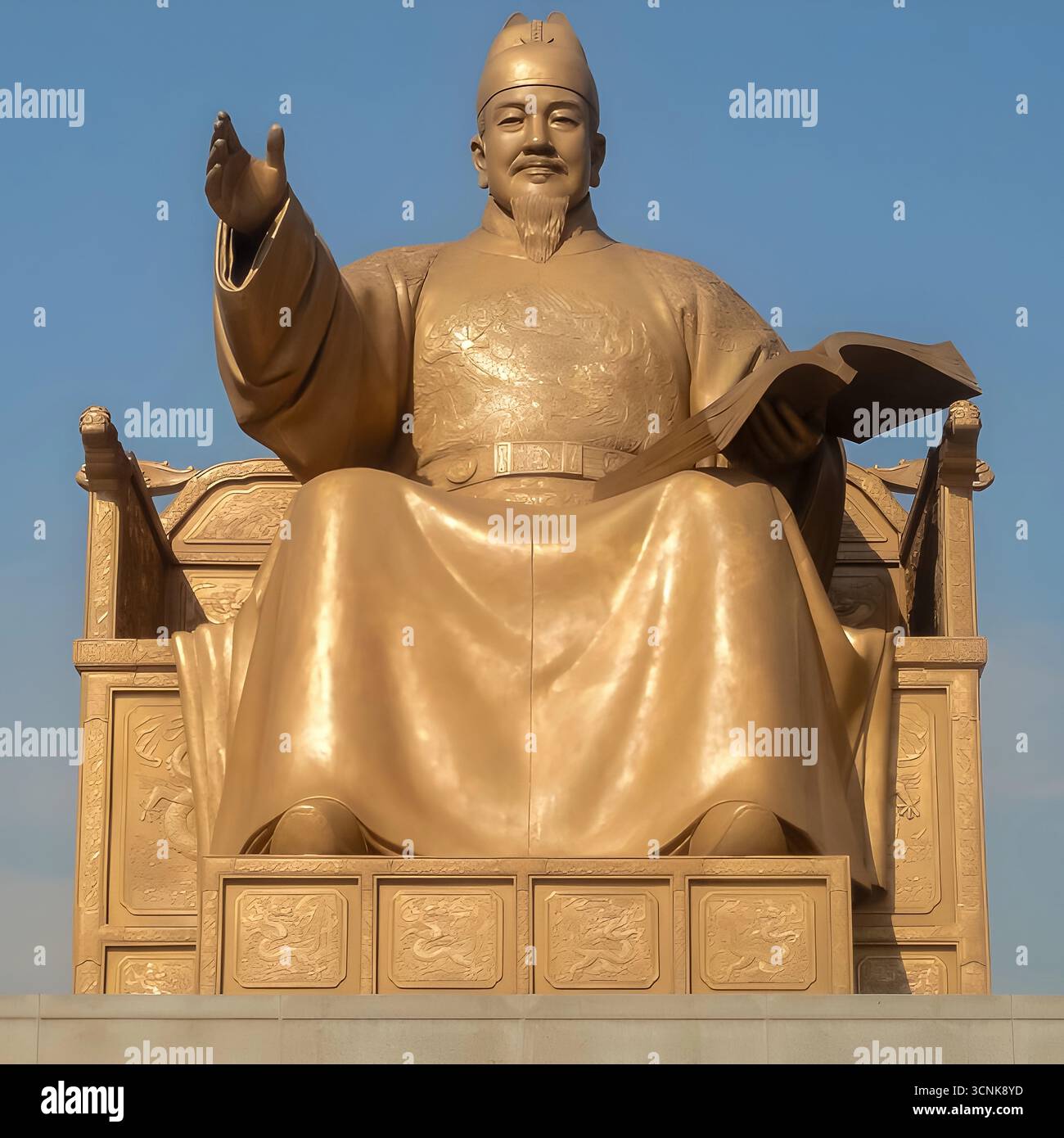 La statua in bronzo dorato del re Sejong il grande, che tiene un libro e gesta con una mano alzata, sotto un cielo azzurro limpido a Seoul, Corea del Sud. Foto Stock