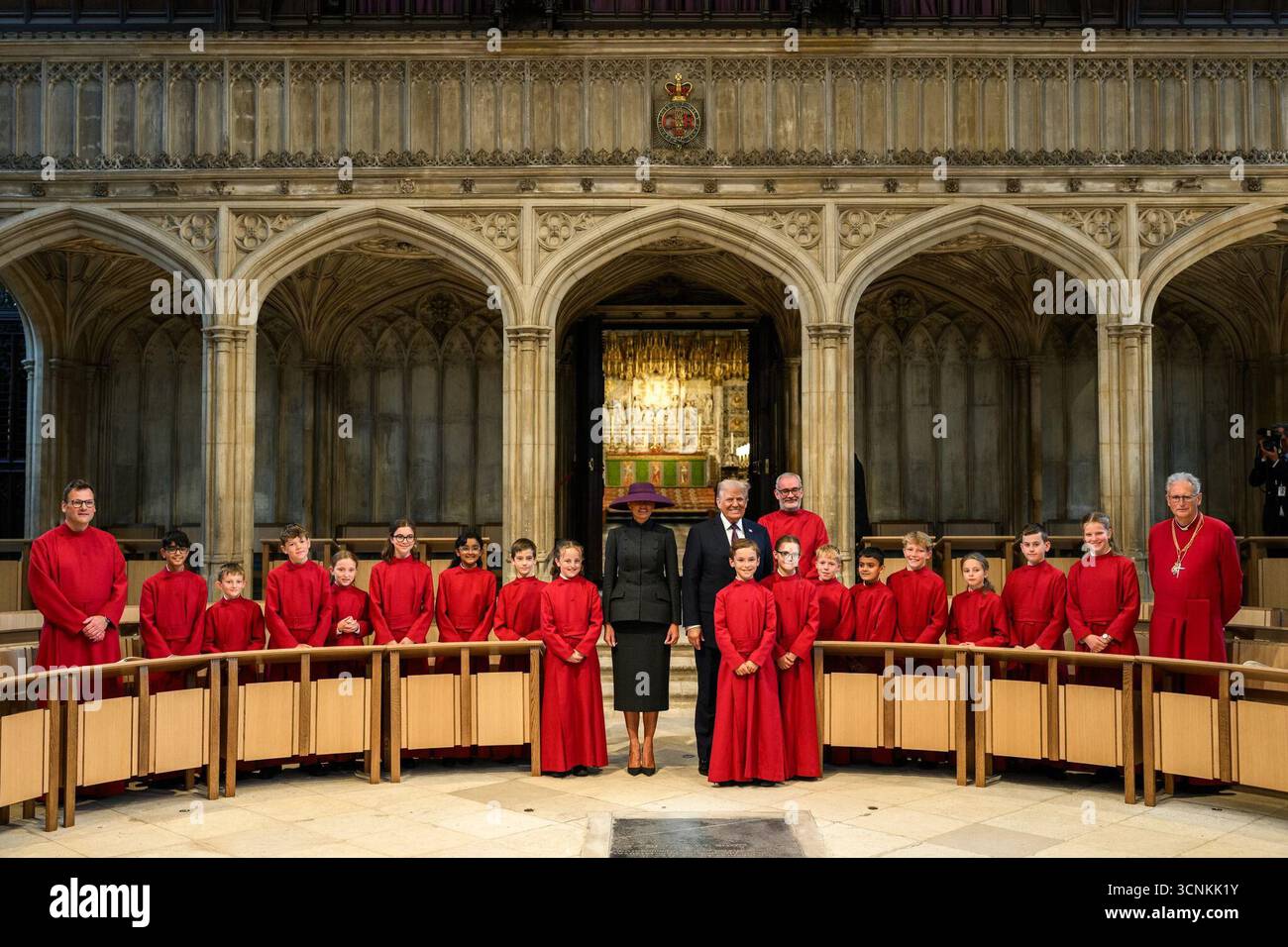 Il presidente degli Stati Uniti Donald J. Trump e la First Lady Melania Trump posano con i membri del coro vestiti di abiti rossi all'interno della St. George's Chapel al Castello di Windsor, in Inghilterra, durante la loro visita di stato. 17 settembre 2025. Per gentile concessione della Casa Bianca. Foto Stock