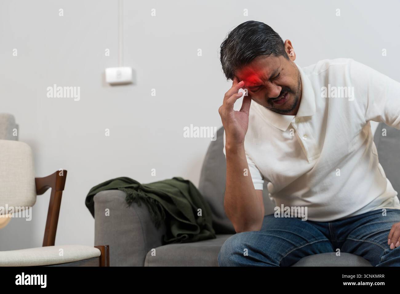 Ritratto di un uomo che tiene la testa con espressione dolorosa ed evidenziazione rossa sulla fronte, simbolo di emicrania, stress, cefalea, malattia, problema di salute, med Foto Stock