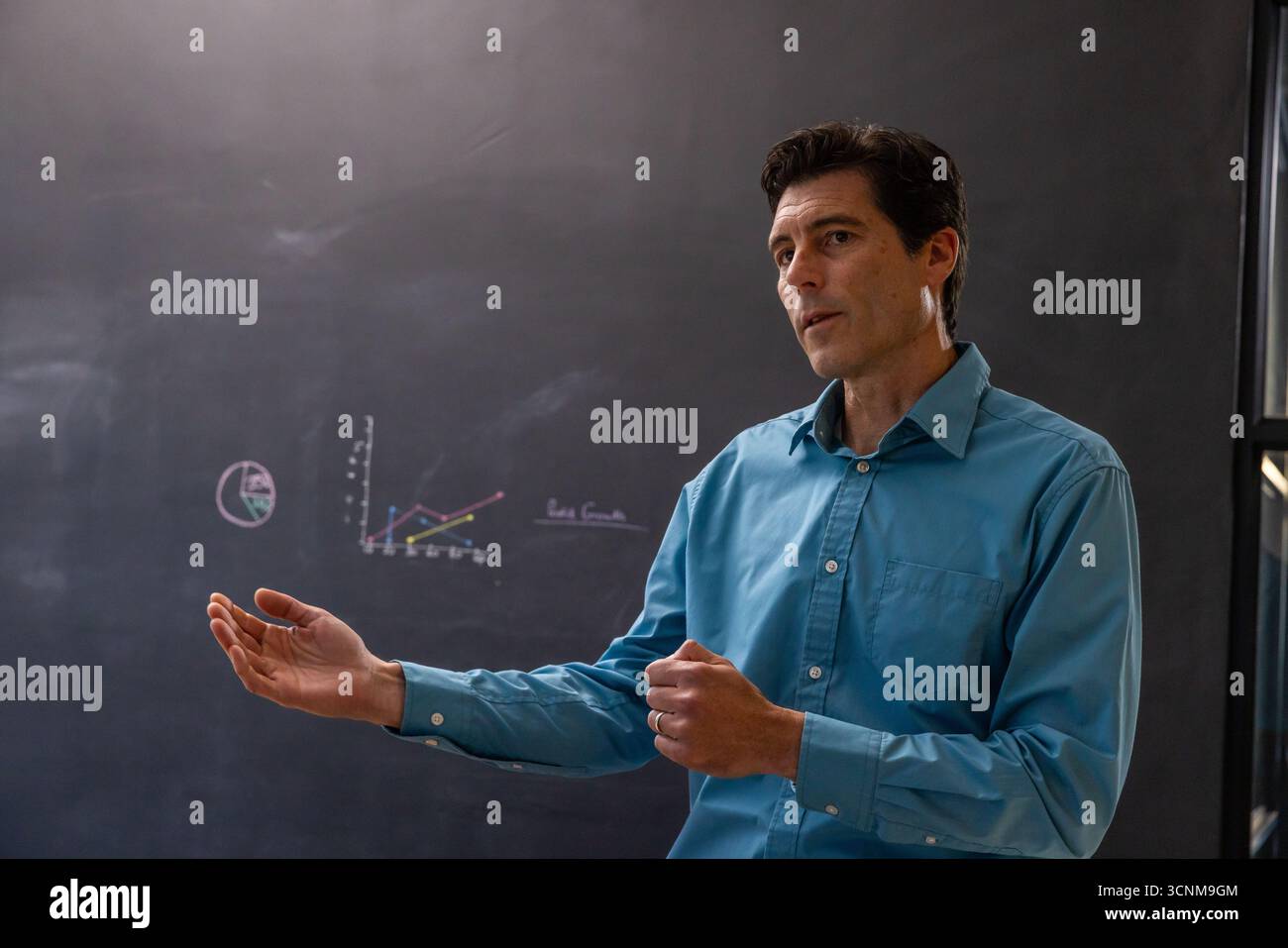 Gesto di uomo bianco mentre si spiegano i diagrammi del grafico sulla lavagna in classe, copiare lo spazio Foto Stock