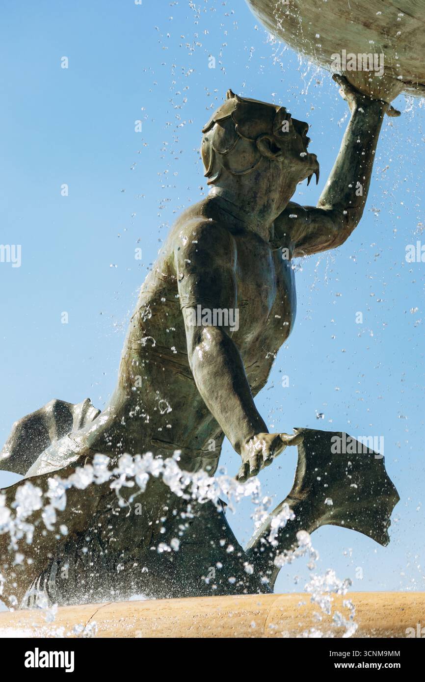 Fontana dei Tritoni all'ingresso di la Valletta, tre divinità mitologiche del mare in bronzo che sostengono un grande bacino, con getti d'acqua scintillanti sotto il limpido Foto Stock