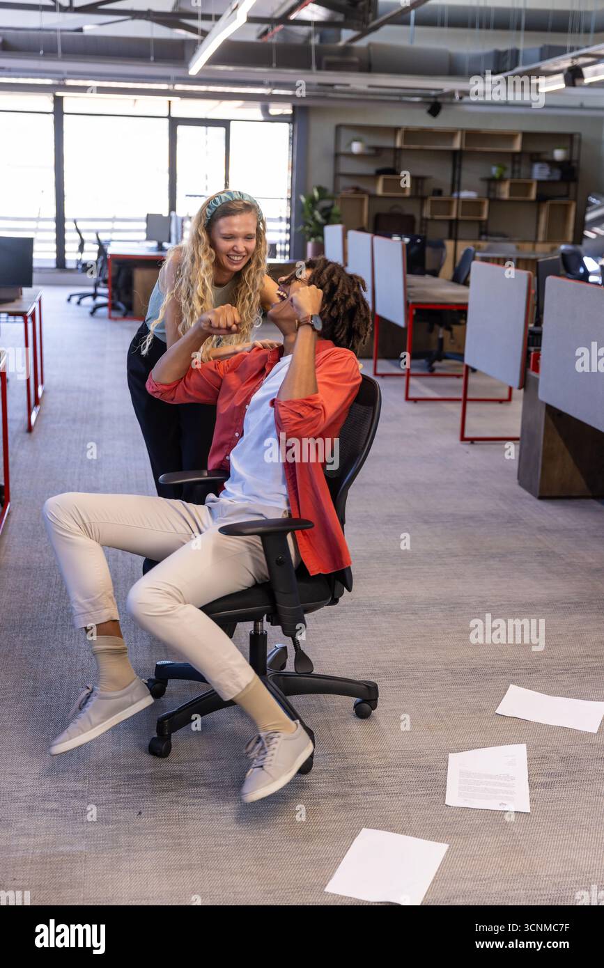 Colleghi diversi che celebrano il traguardo in un ufficio open space con smartphone e monitor per computer Foto Stock