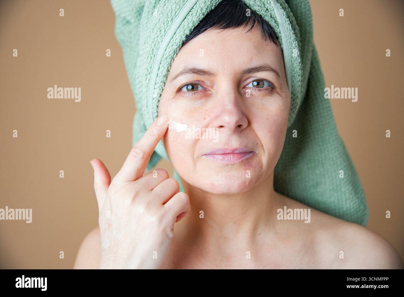 Donna di mezza età con problemi di pelle applicazione nutriente antietà trattamento della crema per la cura della pelle del viso Foto Stock